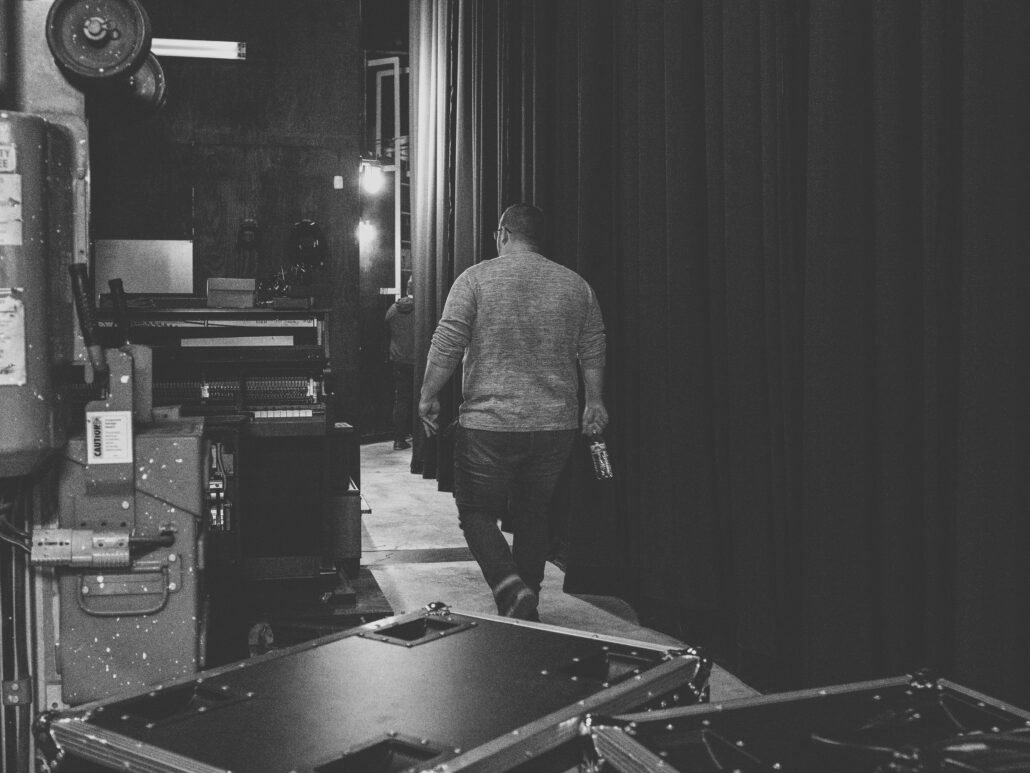 Man walking backstage behind black curtain